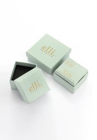 Quadratische Geschenkschachteln aus hellgrünem Papier mit goldenem Text. Eine Schachtel ist geöffnet und zeigt ein schwarzes Innere. Enthält drei Schachteln verschiedener Größen.