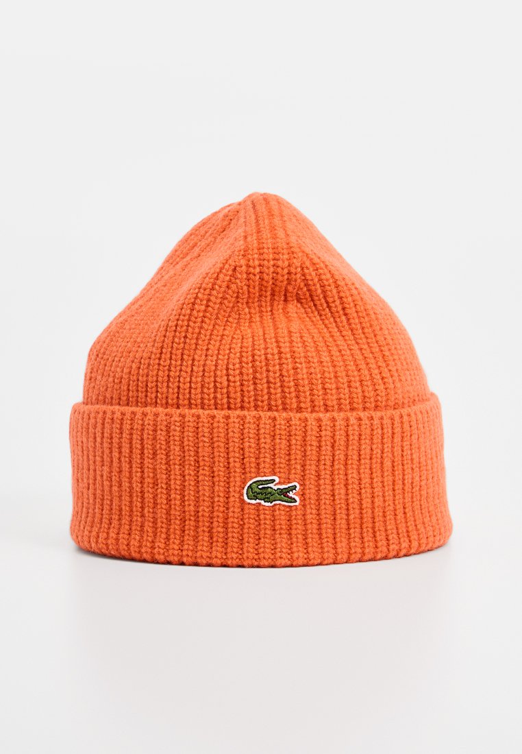 Pomarańczowa dziana czapka z wywiniętym brzegiem, z małym, haftowanym na zielono logo krokodyla z przodu. Teksturowana żebrowana tkanina.