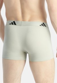 Šedé bavlněné boxerky s černým elastickým pasem, který je zdoben třemi černými pruhy, s hladkou texturou a přiléhavým střihem.