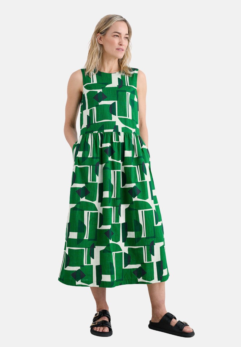 Grünes, gemustertes Kleid mit ärmellosem Design, tailliertem Schnitt und ausgestelltem Rock. Es hat große geometrische Formen in kontrastierenden Farben.