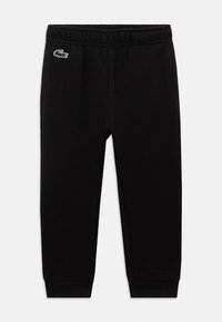 Calças de jogging pretas com cintura elástica e punhos em malha, com um pequeno logo de crocodilo verde no lado superior esquerdo.