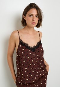 Camicole marron avec imprimé léopard noir et beige, dentelle le long de l'encolure, bretelles fines et coupe décontractée, avec fentes sur les côtés.