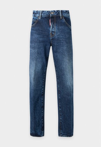 Jean en denim bleu avec légère décoloration sur les cuisses, fermeture avant par bouton et zip, poches avant, passants de ceinture et étiquette de marque rouge près de la fermeture éclair.
