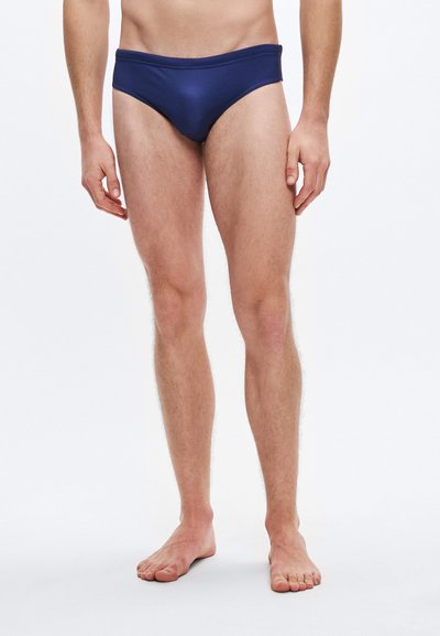 Navy blue swim briefs with a smooth texture, low-rise waist, and minimal coverage, designed for comfort and flexibility.