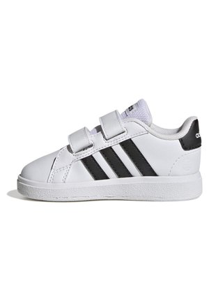 Witte Adidas sneaker met zwarte strepen, twee klittenbandsluitingen en een gestructureerde zool, weergegeven vanaf de buitenkant op een witte achtergrond.