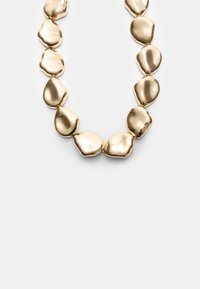 Collana in tonalità oro con link irregolari, levigati e simili a ciottoli, caratterizzati da una superficie liscia e lucente, che formano una catena continua.