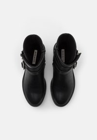 Botines negros de tobillo en cuero suave con punta redondeada, puño ancho y detalle de hebilla plateada. El interior cuenta con un forro suave.