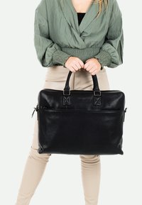 Schwarze Ledertasche für Laptops mit zwei oberen Griffen, glatter Textur, rechteckiger Form, einer Vorderreißverschlusstasche und dezenten Steppdetails.
