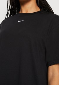 Czarna bawełniana koszulka z krótkim rękawem, okrągłym dekoltem i białym logo Nike na piersi. Miękka faktura, luźny krój.