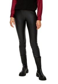 Leggings en cuir synthétique noir au design épuré et ajusté, associés à des bottes noires à semelle épaisse et à un haut bordeaux à manches longues.
