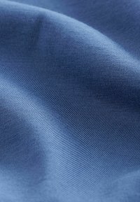Sininen kangas, jossa on sileä pinta ja hienovaraisia nauhakuvioita. Materiaali näyttää kevyeltä ja joustavalta.