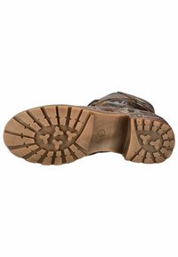 Suela de bota de cuero marrón con un patrón de relieve resistente, que cuenta con profundas ranuras y flechas para mayor tracción; material suave y duradero con un diseño robusto.