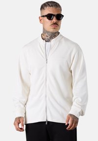 Weißer Reißverschluss-Sweatshirt aus weichem Material mit hohem Kragen und Frontreißverschluss. Verfügt über lange Ärmel und dezente Branding auf der Brust.