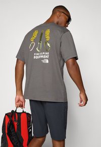 Gray cotton t-shirt featuring a graphic with climbing gear on the back. Notable text "FINE ALPINE EQUIPMENT" and logo in white.