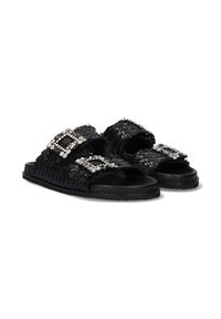 Sandalias tejidas negras que presentan dos correas anchas adornadas con hebillas de strass. La suela es plana y tiene una superficie texturizada para mayor agarre.