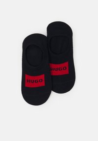 Juodos nematomos kojinės su raudonu stačiakampiu akcentu, kuriame yra žodis "HUGO" juoda spalva. Lygus audinys ir švelni tekstūra užtikrina komfortą.