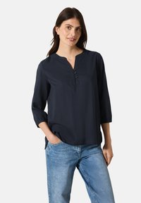 Blusa azul marino con escote en V, mangas de tres cuartos y detalle de botones. Fabricada con un tejido ligero, presenta un corte relajado y un dobladillo redondeado.