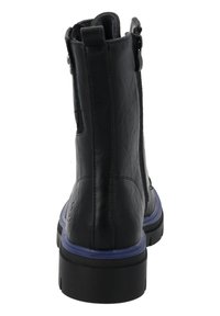 Botín negro con una superficie de cuero texturizado, cremallera lateral y suela morada en contraste. Presenta una puntera redondeada y un tacón grueso.