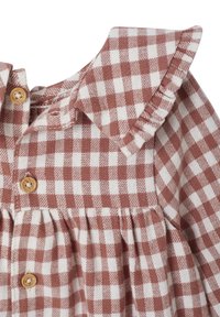 Braun-weiße Gingham-Bluse mit Rüschensaum und Holzknopfdetails; weicher Stoff mit gerafftem Taillenbund für eine lockere Passform.