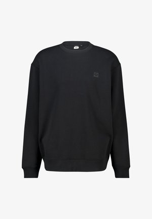 Sudadera negra hecha de una tela suave, con cuello redondo, mangas largas y un pequeño parche de logo en la parte izquierda del pecho.