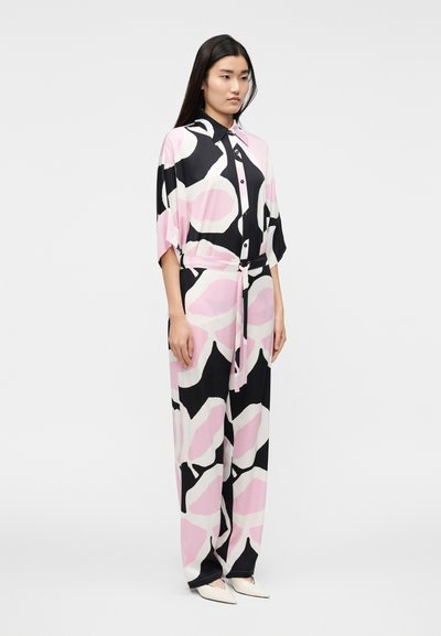 Rosa och svart mönstrad tvådelad outfit med en lös skjorta och vida byxor. Tyget är mjukt med ett bältesdetalj i midjan.