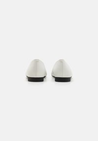 Ballerine bianche in pelle con una superficie liscia, punta affusolata e suole in gomma nere. Design minimalista con sottili dettagli di cucitura.