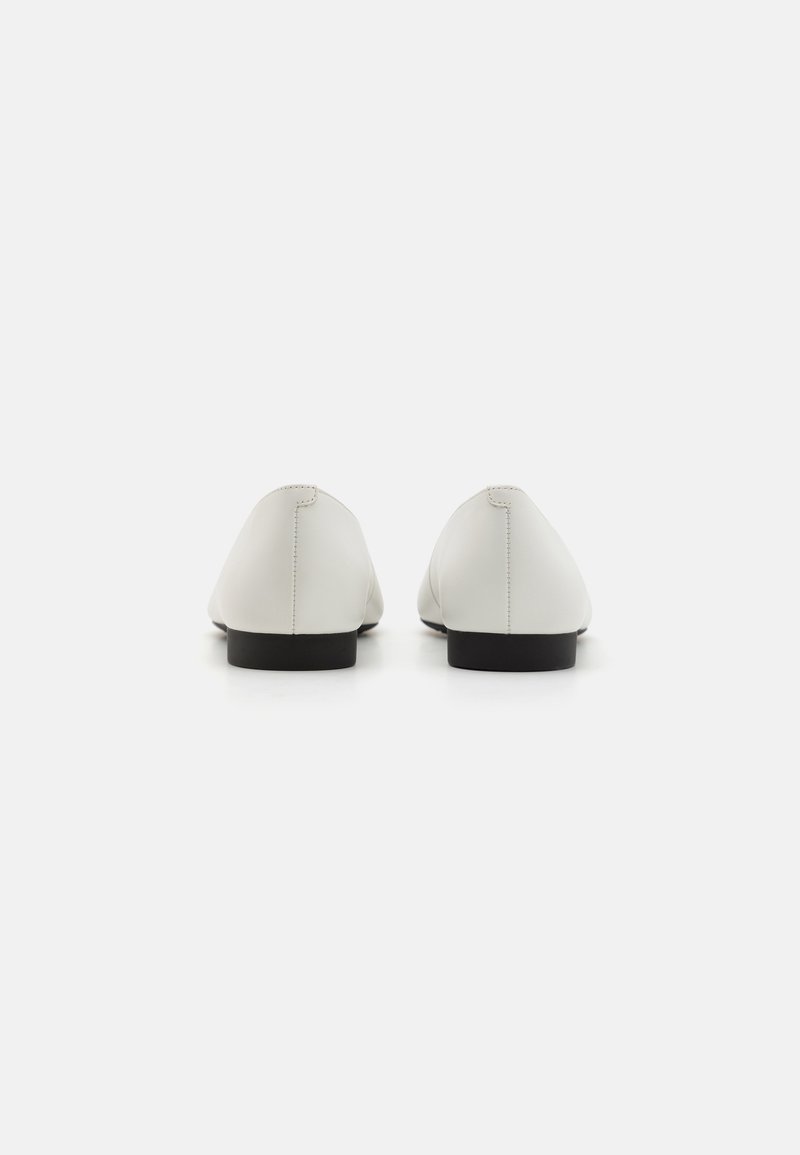 Bailarinas de cuero blanco con textura suave, punteras afiladas y suelas de goma negra. Diseño minimalista con sutiles acentos de costura.