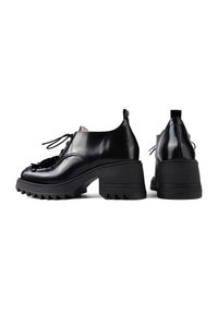 Scarpe in pelle verniciata nera con tacco spesso e texturizzato, design con lacci e decorazioni floreali sulla punta. Suola con battistrada.
