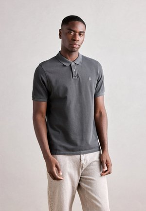 Mørkegrå polo-shirt med krave, tre knapper og et lille logo. Lavet af blødt bomuldsstof, parret med lyse jeans.