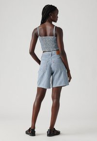 Blå och vit randig crop top med smockad baksida och spaghettiremmar, tillsammans med högmidjade shorts som också har en randig design.