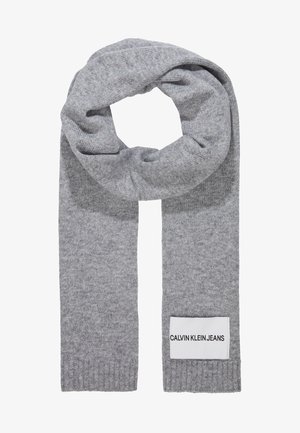 Jasnoszary dziany szalik z naszywką Calvin Klein Jeans przyszytą blisko końca, pokazany złożony w pętlę.