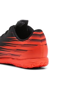 Schwarz-orangefarbener Sportschuh mit strukturiertem Obermaterial, das horizontale Streifen aufweist, und einer Gummilaufsohle, die für guten Halt ausgelegt ist.