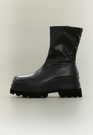 Black mid-calf platform boot with chunky lug sole and smooth leather upper against a plain light background.