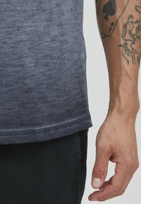 Mørkeblå, kortermet t-skjorte med gradientdesign og teksturert overflate. Har en liten merke-logo nederst og detaljerte sømmer.