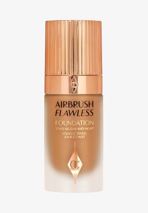Airbrush Flawless Foundation in einer Glasflasche mit einem Farbverlauf von beige zu transparent. Goldfarbener, gerippter Deckel und Logo auf der Vorderseite.