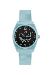 Montre en silicone bleu clair avec un cadran rond noir présentant un design graphique blanc. Comprend des marques horaires et un bracelet texturé.