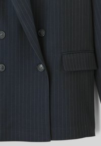 Blazer double boutonné à rayures navy avec de grands boutons noirs et une poche poitrine unique. Coupe ajustée et tissu texturé.