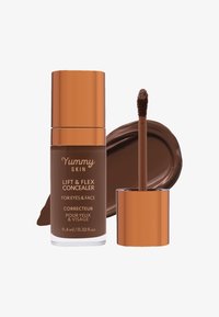 Lift & Flex Concealer i en brun glassflaske med gullkapsel, med en doe-foot applikator og en stripe av rik brun krem.