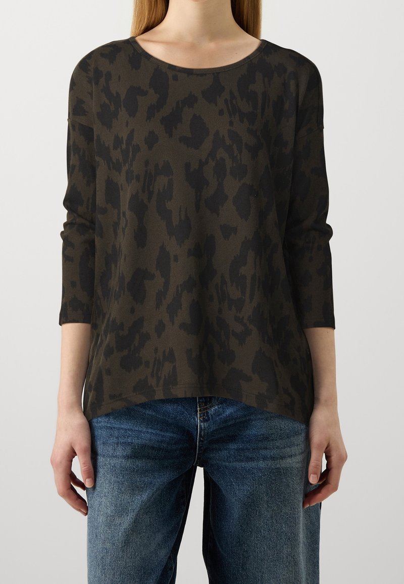 Top verde scuro con stampa leopardata nera, collo rotondo e maniche a tre quarti, abbinato a jeans in denim blu.