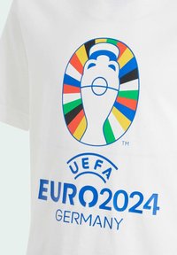 Camiseta blanca de algodón con un colorido logo de la UEFA Euro 2024 que incluye una mano y un fondo estilizado. Texto en azul: "EURO 2024 ALEMANIA."