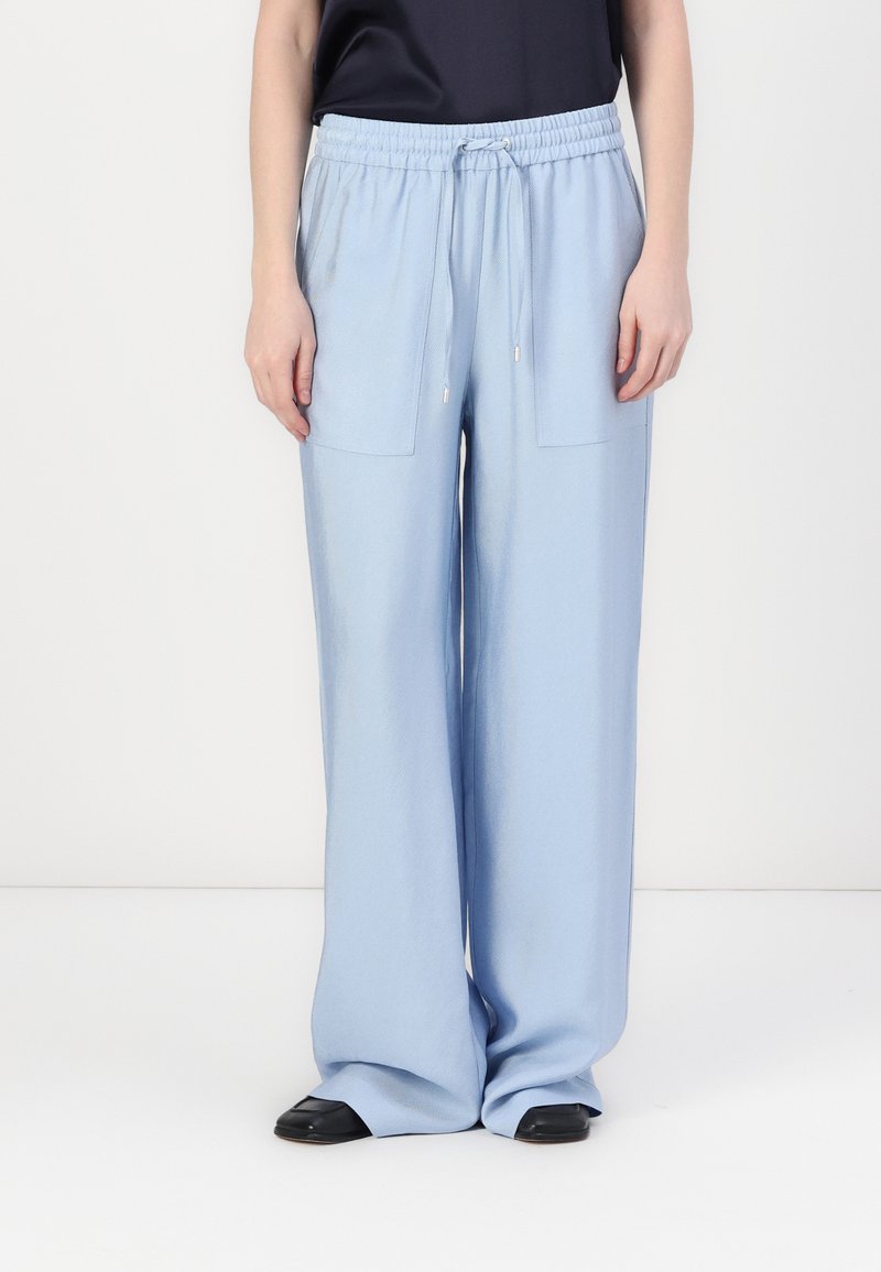 Pantalones de pierna ancha en azul claro con cinturilla elástica, cordón y dos bolsillos exteriores; textura suave y ajuste relajado.