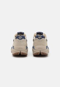 Încălțăminte de drumeție bej și bleumarin, cu un superior din suede și plasă, talpă Vibram și guler căptușit. Tocul este accentuat cu un etichete cu logo.