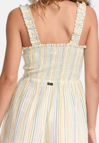 Stropeløs jumpsuit i let, blød stof med lodrette, flerfarvede striber (gul, blå, grøn) og flæsekanter. Har elastisk talje.