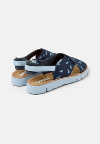 Siniset ja vaaleansiniset avonaiset sandaalit, joissa on kuviolliset hihnat, säädettävät kantabändit, korkkipohjat ja paksut vaaleansiniset pohjat.