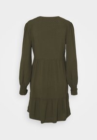 Vestido verde oliva hecho de tela texturizada, con mangas largas, dobladillo en capas y escote redondo. Incluye un patrón sutil en toda la prenda.