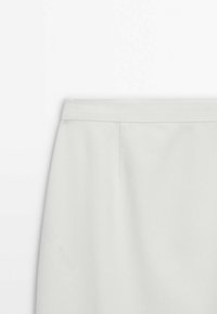 Jupe droite blanche taille haute avec une ceinture ajustée et un détail de couture à l'avant, présentée sur un fond blanc.