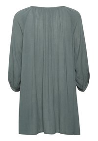 Langärmliges Kleid aus weichem, strukturiertem grünen Stoff, mit einer lockeren Silhouette, gerafften Details am Rücken und ausgestellt gesäumten Ärmeln.