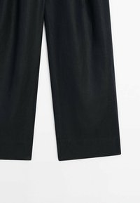 Pantalon noir ample en tissu lisse, avec une coupe droite et des ourlets finis. Pas de motifs visibles ni de matériel supplémentaire.