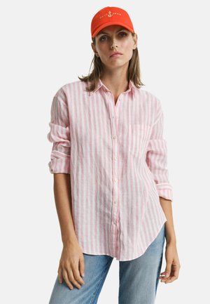 Roze en witte gestreepte button-up shirt gemaakt van lichtgewicht stof, met een zak en opgerolde mouwen, gecombineerd met een feloranje pet.