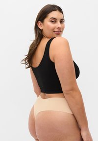 Débardeur court noir à rayures avec sous-vêtements nude sans coutures. Le tissu est doux, extensible et lisse, sans coutures visibles.